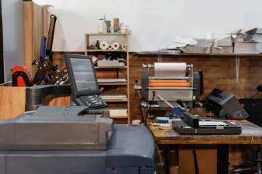 Monitör ve kağıt budayıcının yanındaki modern yazdırma merkezi ekipmanı 