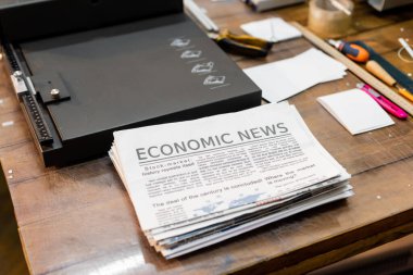 Profesyonel kağıt budayıcı makinesinin yanında ekonomi haberleri olan gazetelerin yüksek açılı görüntüsü 