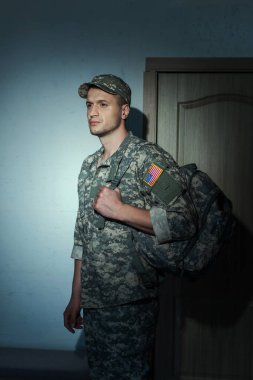 Kamuflajlı hoşnutsuz Amerikan askeri gecenin bir yarısı evin koridorunda dikiliyor. 