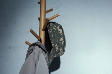 Military cap hanging on floor hanger at home at night  clipart