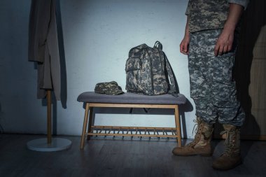 Cropped view of military veteran standing in hallway at home at night  clipart