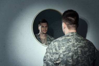 Blurred military veteran with emotional distress looking at mirror at home  clipart