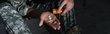 Top view of veteran with mental disorder pouring pills on hand at home at night, banner  clipart