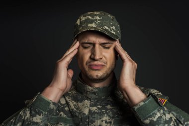 patriotic soldier in camouflage uniform and cap suffering from ptsd isolated on black  clipart