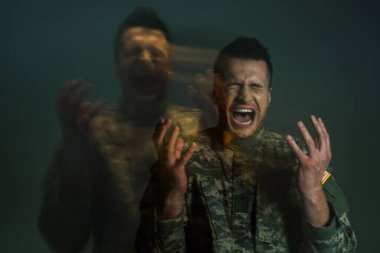 Long exposure of serviceman in uniform screaming while suffering from dissociation disorder isolated on dark grey  clipart