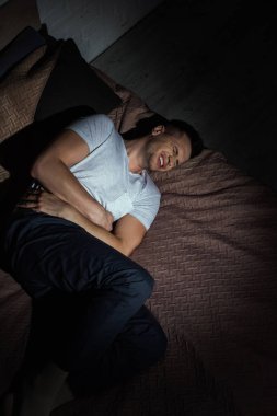 Geceleri yatakta yatarken travma sonrası stres bozukluğundan muzdarip depresif bir adamın üst görüntüsü. 