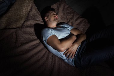 Geceleri yatakta yatarken panik atak geçiren, gözleri kapalı depresif bir adamın üst görüntüsü. 