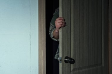 cropped view of serviceman in military uniform opening door while entering room  clipart