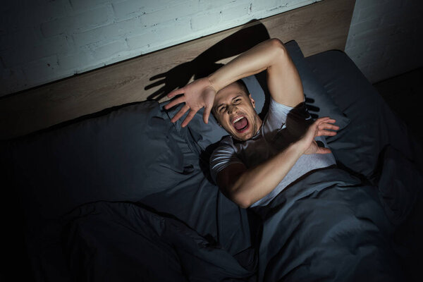 top view of stressed man screaming while having nightmares and panic attacks at night 