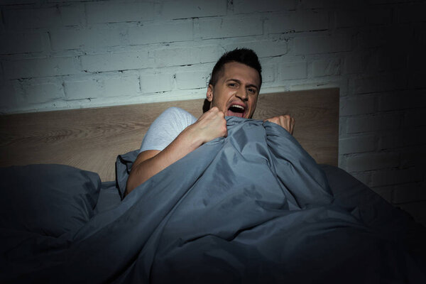 scared man with panic attacks screaming while having nightmare at night 