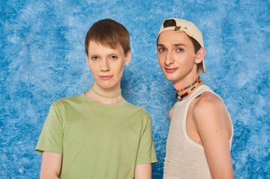 Lgbtq 'ın renkli boncukları ve günlük kıyafetleriyle genç arkadaşları gurur ayında mavi arka planda yan yana dururken kameraya bakıyorlar. 