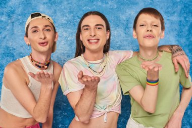Kaygısız homoseksüel arkadaşlar, günlük kıyafetleriyle kameraya sarılıp hava öpücüğü verirken aynı zamanda LGBT 'nin gurur ayını mavi arka planda kutluyorlar.