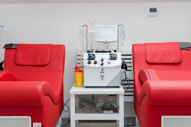 Otomatik nakil makinesinin, dokunmatik ekranın, plastik bardağın ve damlaların yanında ergonomik tasarımı olan tıbbi sandalyeler kan bağışı merkezinde kan torbalarıyla birlikte.