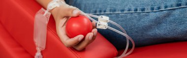 Kan nakli seti ve plastik top taşıyan çok ırklı bir kadının rahat ve ergonomik tıbbi sandalyeye oturup hastaneye kan bağışlaması, afiş...