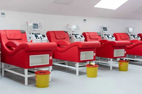 タッチスクリーンを備えた輸血機の近くの現代的で快適な医療椅子の列 点滴スタンド輸液バッグ 血液提供センターの滅菌環境でのゴミバケツ — ストック写真