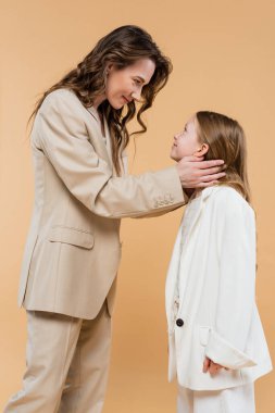 mother child bonding concept, happy woman in suit hugging cheerful preteen daughter and standing together in suits on beige background, corporate mom, businesswoman, motherly love  clipart