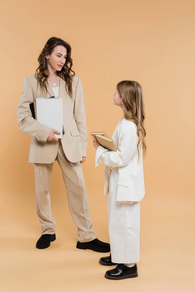 ベージュを背景に立ちながらスーツ姿の現代家族 女性と子供の本やノートを持っている 正式な服装 企業ママ 教育概念 — ストック写真