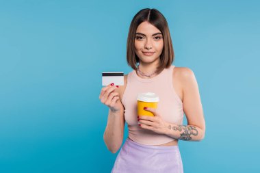 to go coffee, happy young woman with short hair, tattoos and nose piercing holding paper cup and credit card on blue background, generation z, summer trends, attractive, coffee culture  clipart