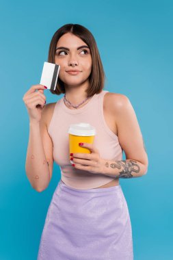 to go coffee, young woman with short hair, tattoos and nose piercing holding paper cup and credit card on blue background, generation z, summer trends, attractive, coffee culture, dream clipart