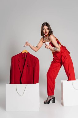 Tüketim, kısa saçlı ve burnu piercingli, spor ceketli ve alışveriş çantalarının yanında akıllı telefon kullanan, modern moda eğilimli, uzun boylu bir kadın. 