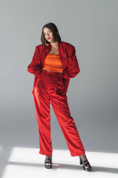 модный наряд, молодая брюнетка с короткими волосами позирует в костюме на сером фоне, поколение z, модный наряд, модная модель, профессиональный наряд, исполнительный стиль, полная длина 