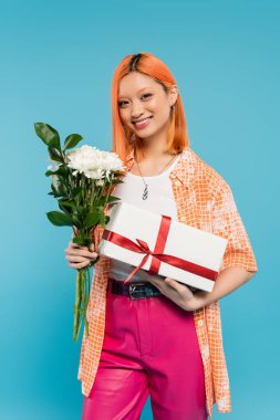 Çiçek buketi, bayram, hediye, neşeli ve genç Asyalı kadın elinde beyaz çiçekler ve mavi arka planda hediye kutusu, günlük kıyafet, z nesli, bayram kutlaması, doğum günü