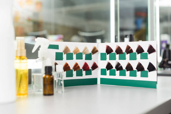 beauty service, hair color palette and different hair salon tools on white surface, hair oil, spray bottles, salon work, hair extension, hair coloring, color selection, blurred foreground 