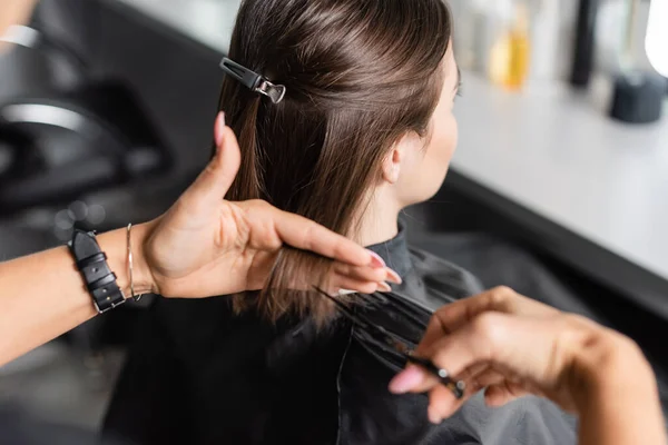 stock image hair salon tools, cropped view of professional hairdresser cutting short brunette hair of woman, hair clip, beauty worker, haircut, beauty salon work, hairdo, scissors