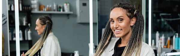 female client in hair salon, cheerful woman with braids looking at camera, customer satisfaction, beauty salon, hairstyle, female client with braids, mirror refection, ponytails, banner 
