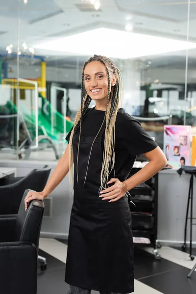 stock image happy hairdresser, woman with braids in beauty salon, hair extension, beauty worker, salon work, hair trends, positivity, interior, profession, salon industry, professional headshots 