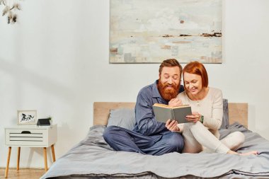 quality time, reading book together, happiness, day off without kids, redhead husband and wife, bonding, happiness, bearded man and woman, relaxation, parents alone at home, lifestyle, adult leisure  clipart
