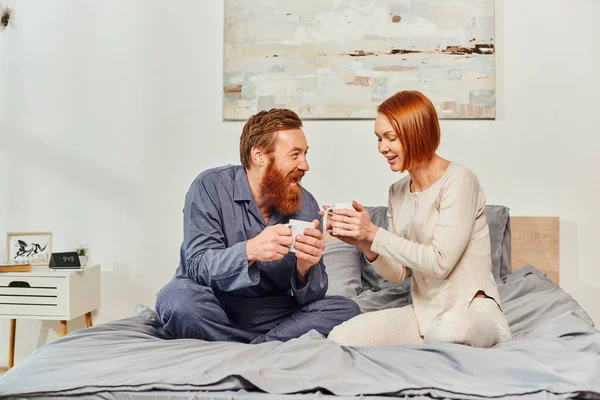 stock image morning rituals, quality time, day off without kids, redhead husband and wife, happiness, bearded man and woman holding cups of coffee, parents alone at home, lifestyle, adult leisure 