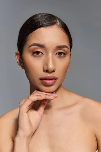 漂亮的亚洲女人 一头乌黑的头发 赤裸的肩膀 灰色的背景 皮肤护理 健康的皮肤 自然美 年轻的模特 干净而明亮的皮肤 看着相机 — 图库照片