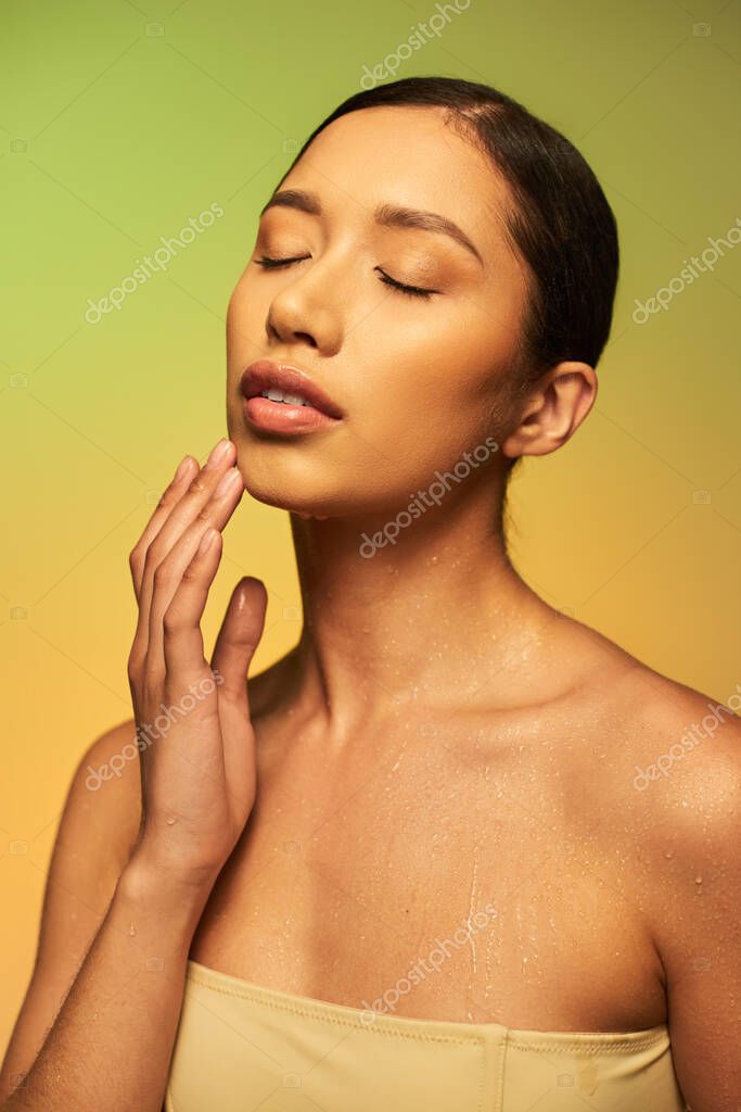 Skin hydration, young asian woman with bare shoulders and wet body posing on gradient background, closed eyes, skincare campaign, beauty model, brunette hair, conceptual