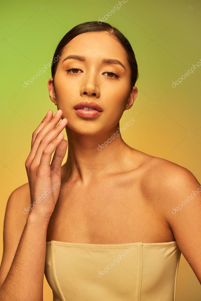 Beauty campaign, skin hydration, asian woman with bare shoulders and wet body posing on gradient background, skin care, looking at camera, young model, brunette hair, glowing skin