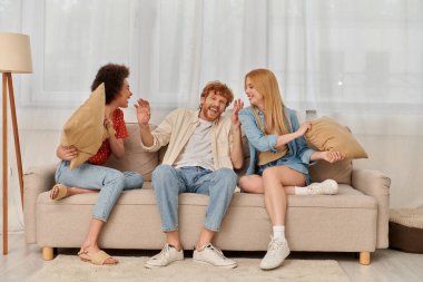 çok eşlilik, grup ilişkisi, mutlu çok kültürlü kadınlar ve sakallı adam yastıklarla kavga ediyor, açık ilişki, çeşitlilik ve bağ, tek eşlilik yok, üç kişi eğleniyor. 