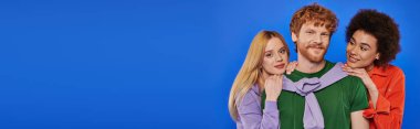 alternative relationships, polygamy, portrait of three people, young redhead man and beautiful multiracial women on blue background, studio shot, vibrant clothes, polyamory, modern family, banner  clipart