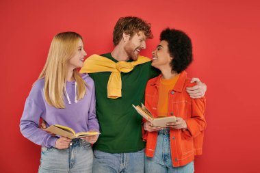 Çok eşlilik ve sevgi, mercan arka planı, kültürel çeşitlilik, çokeşlilik, açık ilişkide çok ırklı, zeki ve neşeli aşıklar hakkında kitaplar tutan ırklar arası insanlar. 