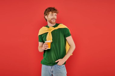 morning coffee, energy, redhead man with beard and curly hair holding paper cup and standing with hand in pocket, on coral background, vibrant colors, male fashion, takeaway drink, hot beverage clipart
