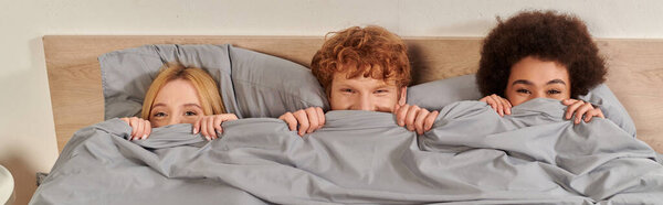 открытые отношения и полигамия концепция, понимание, три взрослых весело, скрываясь под одеялом, рыжий мужчина и мультикультурные женщины, культурное разнообразие, принятие, бисексуалы, баннер 