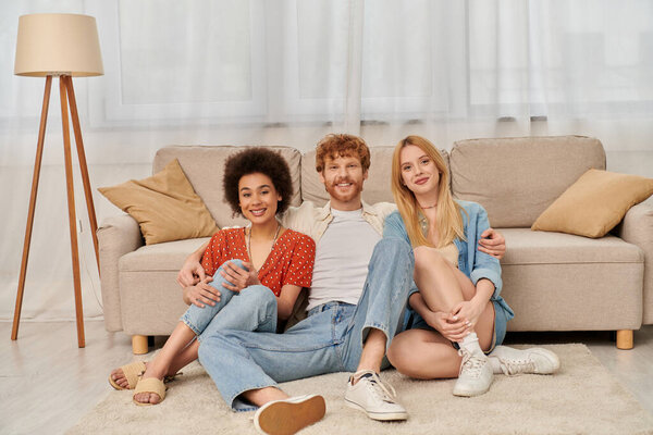 polygamy, acceptance and bonding, group relationship, love triangle, happy multicultural women and bearded man, open relationship, diversity and bonding, non monogamy, three people looking at camera 