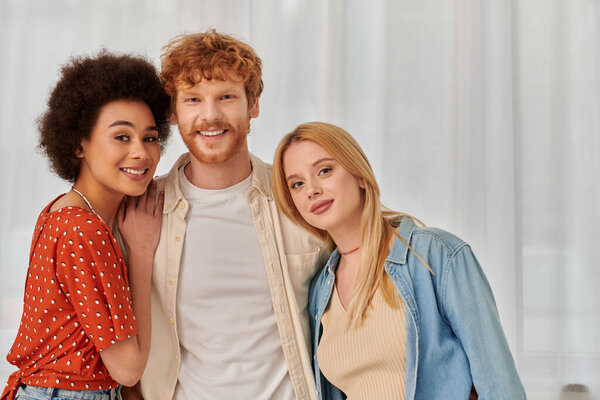 polyamory, multiracial lovers, non traditional relationship, polygamy, three adults, happy redhead man hugging with multicultural women, threesome, cultural diversity, acceptance, bonding and love 
