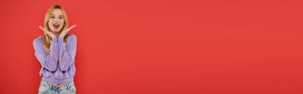 natural beauty, youthful fashion, amazed and blonde young woman in casual attire posing on coral background, happiness, looking at camera, vibrant colors, fashion forward, beautiful, banner 