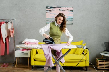 housework concept, beautiful young woman with wavy hair ironing sweatshirt, housewife doing her daily duties, lifestyle, domestic chores, laundry day, home tasks, domestic chores  clipart