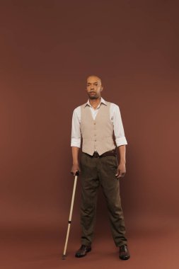 real people, bold african american man with myasthenia gravis syndrome standing with walking cane on brown background, standing and looking at camera, diversity and inclusion, physical impairment  clipart