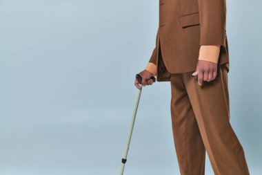 Gerçek insanlar, Afrika kökenli Amerikalı bir adamın gri arka planda bastona yaslanması, koyu tenli takım elbiseli insan, çeşitlilik ve kapsama, yürümede zorluk, otoimmün hastalıklar 