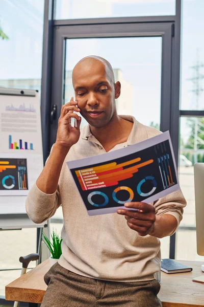 myasthenia gravis, bold african american businessman with eye syndrome having phone call while discussing charts, bold dark skinned office worker holding smartphone, inclusion