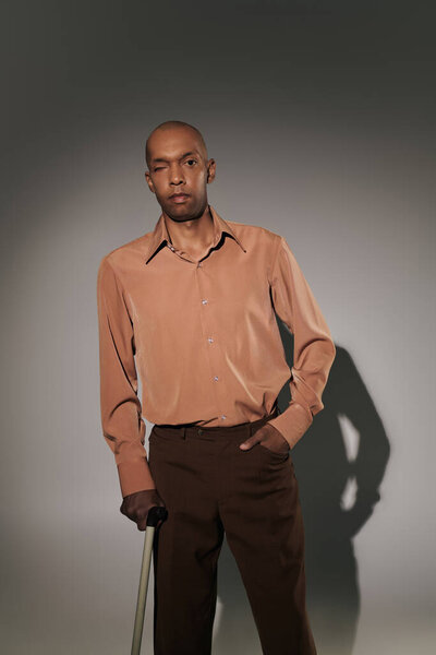 real people, bold african american man with myasthenia gravis standing with walking cane on grey background, hand in pocket, pose, dark skinned person in shirt, diversity and inclusion 