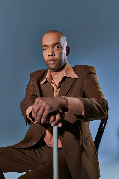 diversity and inclusion, african american man with myasthenia gravis syndrome sitting on chair and looking at camera on blue background, leaning on walking cane, difficulty walking, ptosis 