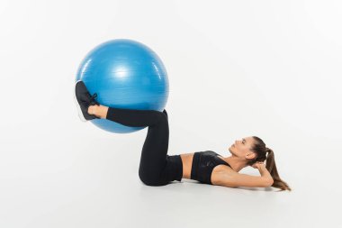 Spor giyimli, beyaz arka planda fitness topu eğitimi alan sağlıklı ve formda bir kadın.